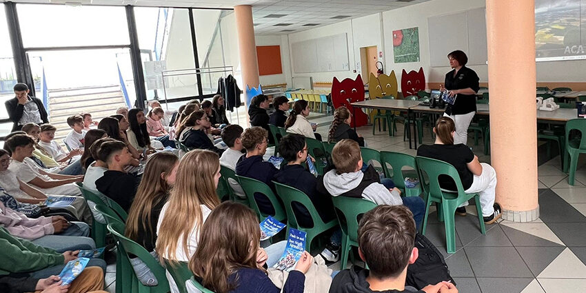 Une salle de classe de l'Aéroclub de l'Aisne remplie de jeunes élèves attentifs suivant une présentation du BIA animée par une instructrice debout devant un écran de projection