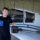 Un jeune pilote de l'Aéroclub de l'Aisne tout juste diplômé, tenant son carnet de vol PPL devant un avion de tourisme dans un hangar.