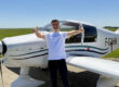 Le jeune pilote Serdem souriant, faisant un double pouce levé devant un avion de tourisme blanc immatriculé F-GAHM sur le tarmac ensoleillé de l'Aéroclub de l'Aisne.